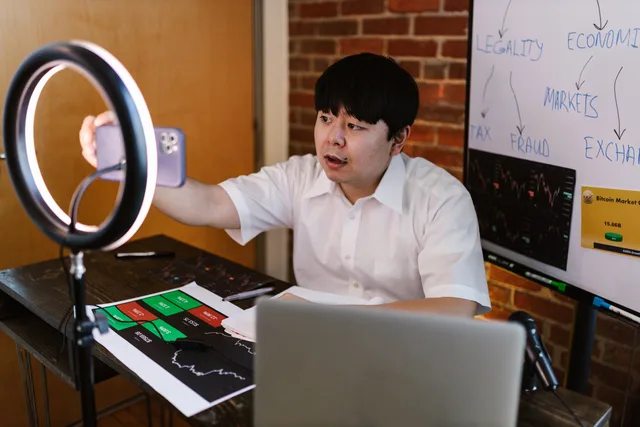 Young man filming a vlogger video about cryptocurrency trading with charts and graphs. Marktdaten zur Creator Economy bewerten